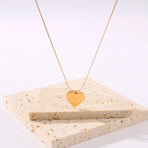 Minimalist 18K gold plated heart pendant necklace displayed on a beige stone block