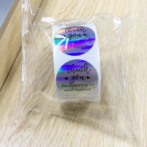 Holographic laser rainbow thank you stickers roll on a light wood background