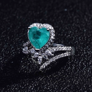 Macro detail of heart-shaped green gemstone ring with pavé diamond halo and floral base