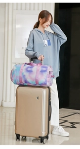 Sac de voyage imperméable à motif tie-dye fixé sur la poignée d'une valise trolley