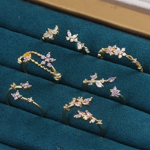 Vue détaillée de bagues dorées avec fleurs et papillons en zircon sur velours sarcelle