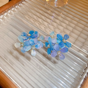 Macro shot of blue-purple gradient flower earrings with pearl stamen on glass texture