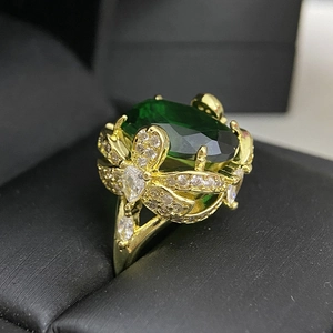 Macro detail of the 18k gold-plated ring with a large green gemstone and white diamonds