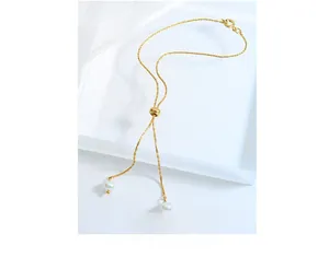 Detail of gold Y-shaped pearl necklace with tassel drops on elegant white setup