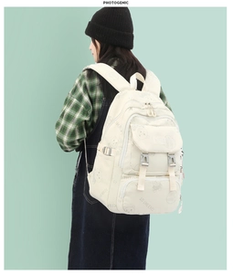 Detail of cream backpack showing cute cartoon bear print and front buckle pocket
