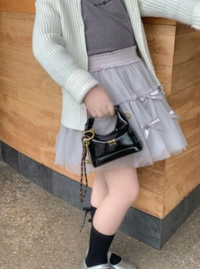 Close-up of black patent leather mini hobo bag with gold hardware and logo for girls