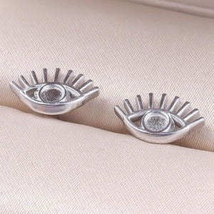 Macro detail of silver stainless steel eye shaped stud earrings in a pink jewelry box