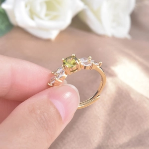 Macro shot of an adjustable gold ring with a green zircon stone on a silk background