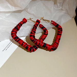 Détail de boucles d'oreilles carrées avec motif léopard rouge et noir et crochets dorés