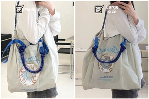 Detail showing the medium and large sizes comparison of donut embroidered nylon tote bags