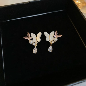 Macro detail of butterfly pearl earrings with zircon water drops on black velvet
