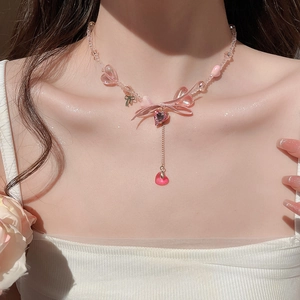Detail of pink resin heart necklace with ribbon bow and beaded chain on a model