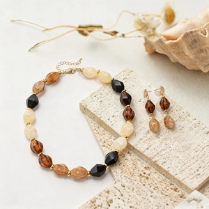 Detail of bohemian resin beaded necklace and earrings set with marble texture and gold accents