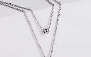 Détail macro du collier à perles argentées avec pendentif rond lisse sur fond blanc