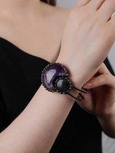 Detail of vintage bronze bracelet featuring purple crescent moon stone on female wrist