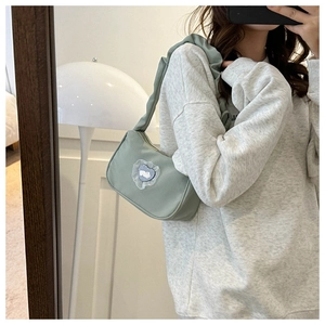 Detail of light green nylon shoulder bag featuring lace heart rabbit patch and mirror reflection