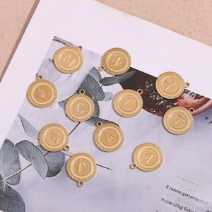 Detailed view of 10 gold striped round pendants with assorted letters on a natural background