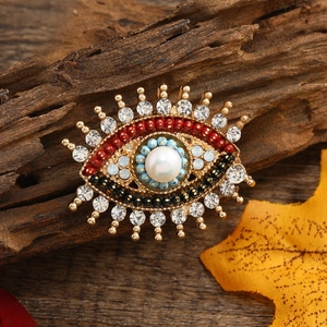 Detailed close-up of Evil Eye brooch with pearl, blue beads and rhinestones on wood