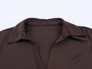 Détail d'une chemise en satin marron foncé avec col en V profond et texture de tissu soyeuse