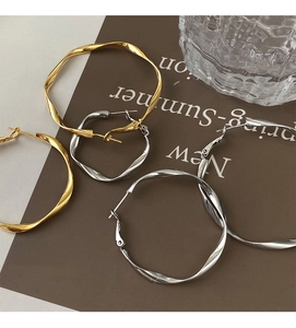Detail of twisted texture hoop earrings in gold and silver finish on artistic display
