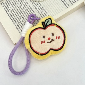 Close-up of a plush yellow apple keychain with cute embroidery on a desk setting