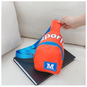 Détail du sac bandoulière enfant orange en nylon avec sangle bleue et logo sport