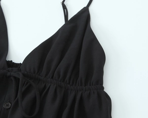 Detailed view of black camisole featuring ruched fabric and decorative buttons decoration