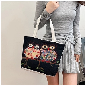 Ethnic style woven canvas tote bag featuring vibrant owl embroidery on a black background