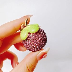 Macro shot of rhinestone-studded mangosteen keychain with purple crystal and gold details