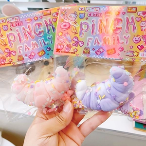 Detail of two croissant-shaped soft pinch toys in pink and purple colors with toppings