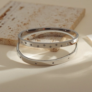 Detail of silver stainless steel bangles with star patterns and inlaid small diamonds