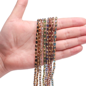 Close-up of hand holding various colorful 4x6mm faceted glass seed beads for DIY jewelry