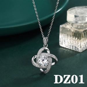 Detailed close-up of a silver four-leaf clover pendant with sparkling zircon on a dark plate