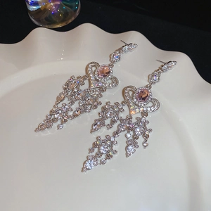 Detailed close-up of silver tassel earrings with pink crystals on a white plate