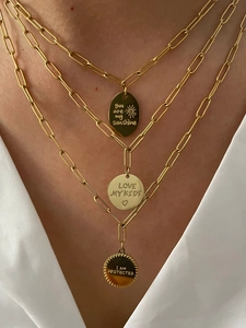 Gros plan d'un collier à trois couches en maillons trombone avec pendentifs gravés inspirants