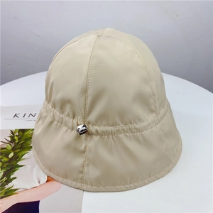 Close-up of beige nylon bucket hat featuring a functional adjustable drawstring buckle