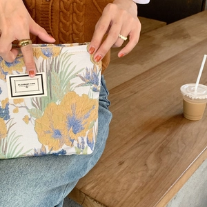 Detail of floral brocade makeup bag with Pleasant Time label and metal zipper closure