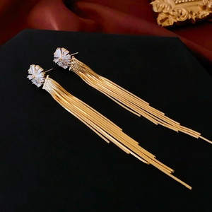 Macro detail of long gold tassel earrings with zircon stones on a luxury background