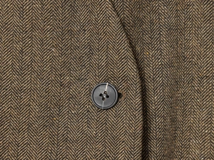 Macro shot of dark brown herringbone tweed fabric with premium resin four-hole button detail