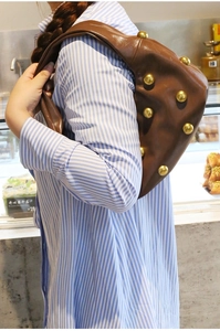 Detail of a brown leather shoulder bag with large gold studs on a vintage hobo bag design