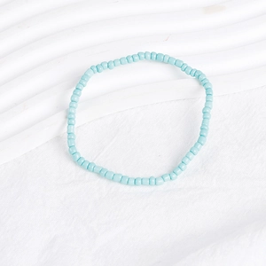 Close-up of a sky blue bohemian beaded bracelet on a wavy white textured background