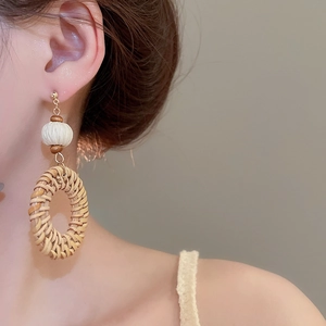 Close-up of Bohemian woven rattan drop earrings with wooden beads on model