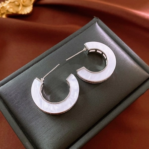 Detail of silver C-shape hoop earrings with white marble inlay on a jewelry box
