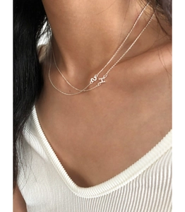 Close-up of layered S925 silver necklaces with H and S initial pendants on model