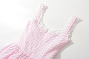 Detailed close-up of pink plaid dress featuring white lace straps and V-neckline trim