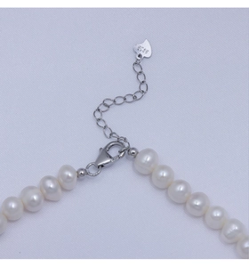 Close-up of S925 sterling silver lobster clasp and heart pendant on pearl necklace