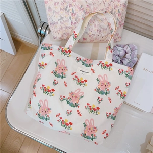 Close-up of cute rabbit and floral print on white canvas tote bag with woven label