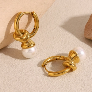 Detail shot of 18K gold knotted metal earrings featuring glossy white pearl pendants