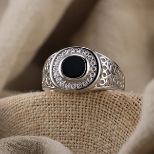 Macro detail of retro s925 silver ring with black onyx and pavé zircon on linen background