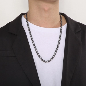 Detail of matte black Figaro chain necklace worn by male model in urban suit